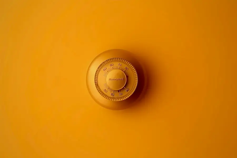 Round thermostat on a bright wall