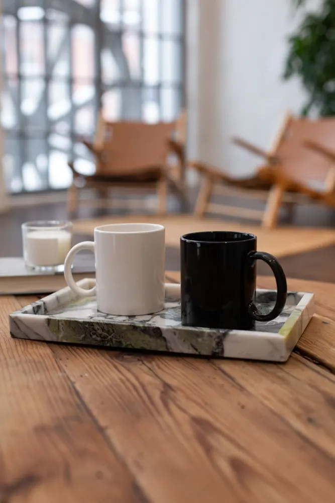 Black and white ceramic mugs on a marble tray